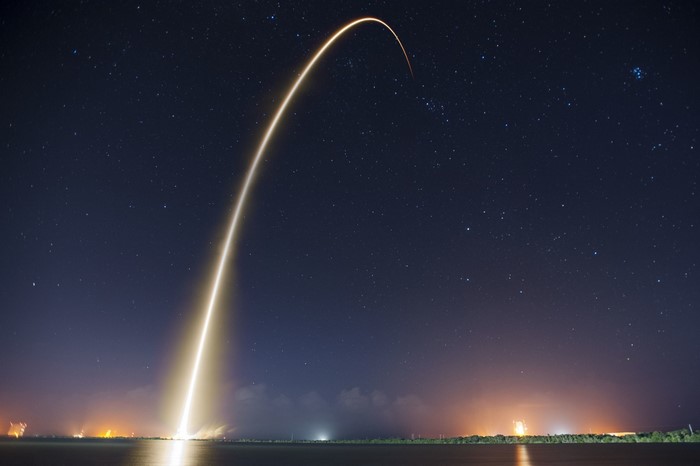 Rocket Launch Trail Against Starry Night Sky Over Water