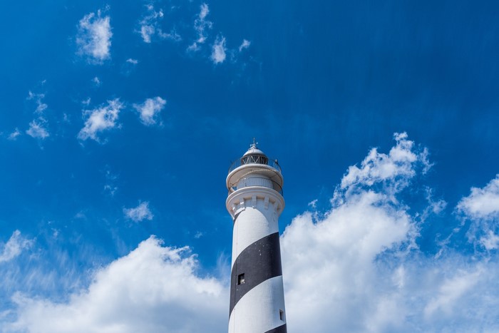Lighthouse against a blue sky with clouds