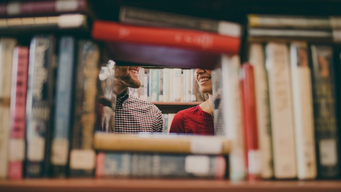 Couple smiling between bookshelves in a library