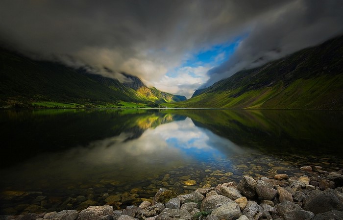 Lake reflection in a Norwegian valley with mountains and clouds