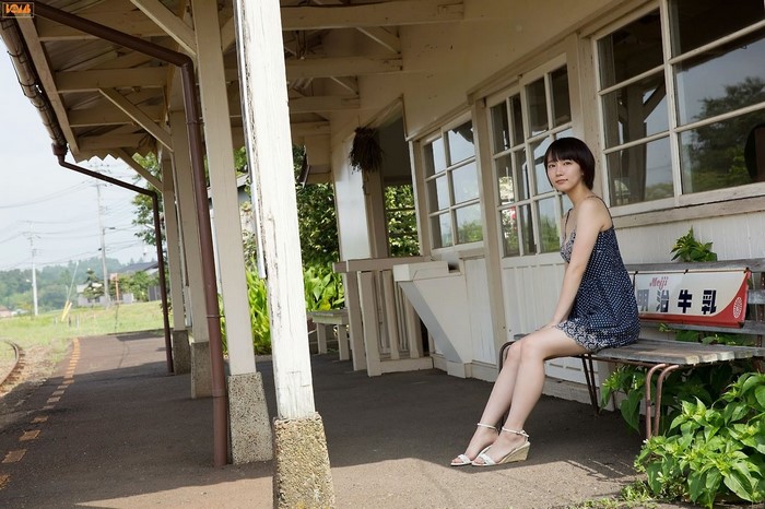 Riho Yoshioka sitting on a bench at a train station