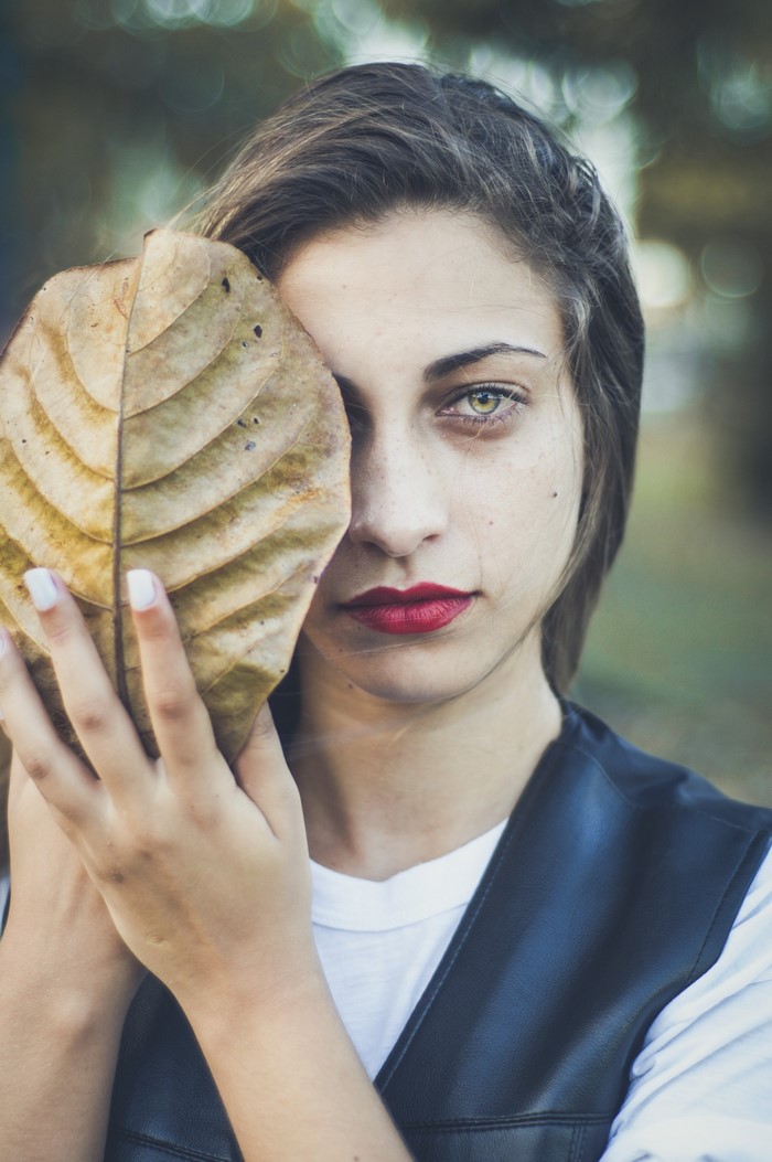 Woman holding a large leaf in front of her face