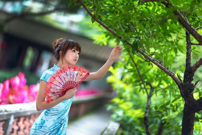 Woman in a blue dress holding a red fan