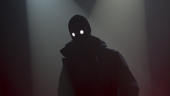 Silhouette with glowing eyes in dark lighting