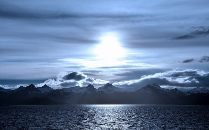 Sunlight over snow-capped mountains and the sea