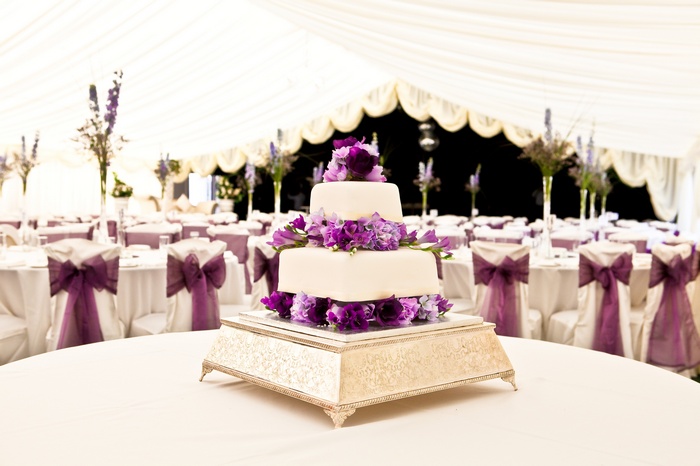 Wedding cake with purple flowers in a tent