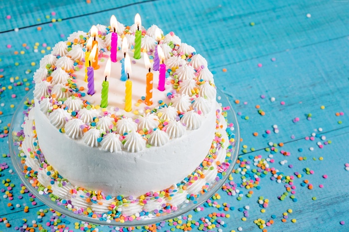 Birthday cake with lit candles and sprinkles