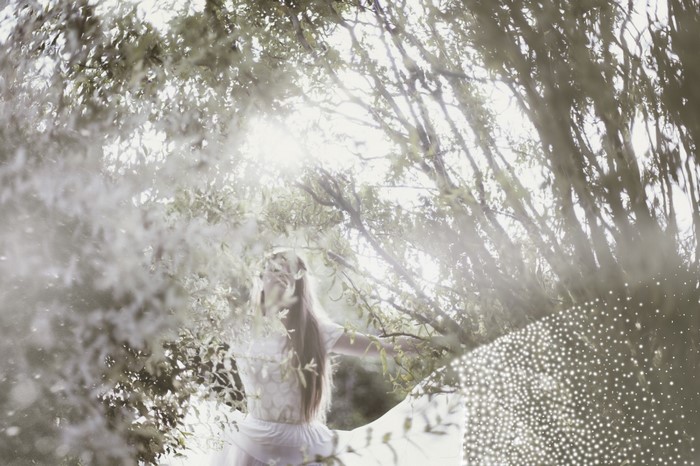 Woman in white dress in sunlit forest