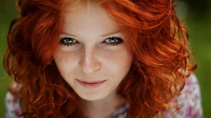 Close-up portrait of a young woman with red hair and freckles