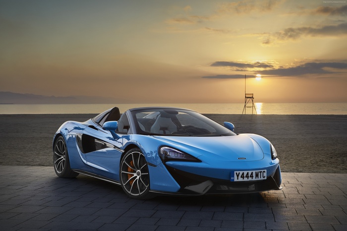 Blue McLaren 570S Spider convertible on beach at sunset