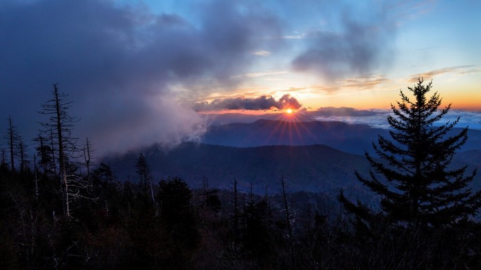 Sunset over mountains with trees and clouds
