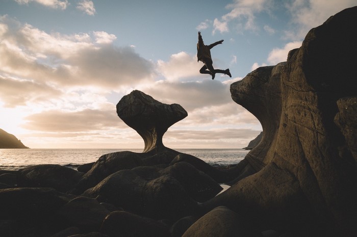 Man jumping between rocks at sunset in Norway