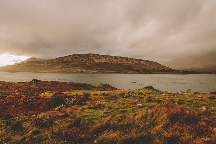 Autumn landscape with a lake and hills under cloudy sky
