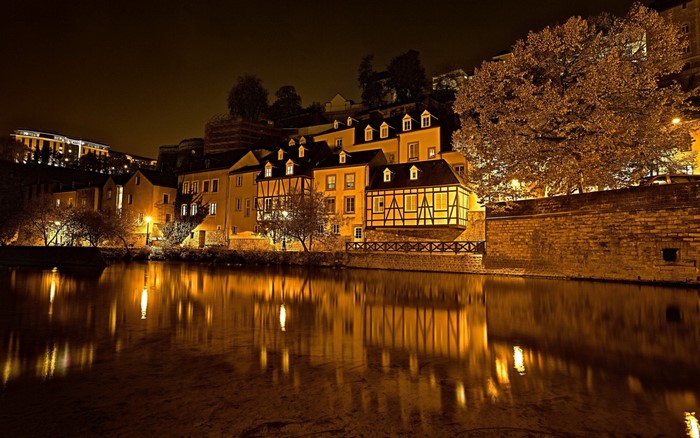 Night cityscape with illuminated buildings and river reflection