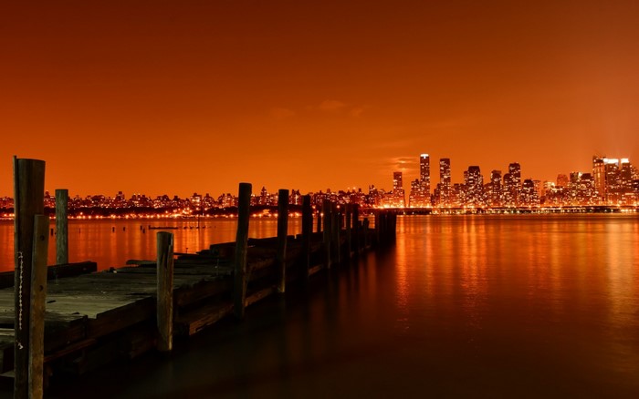 City skyline at night with a wooden pier