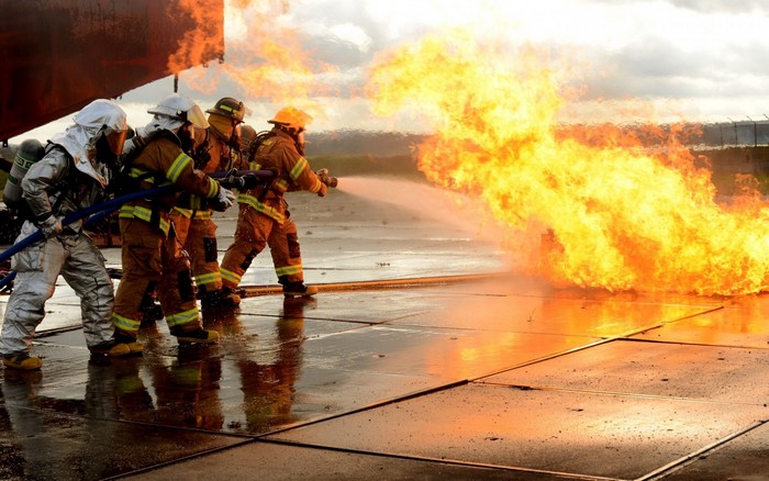 Firefighters battling a large flame with water