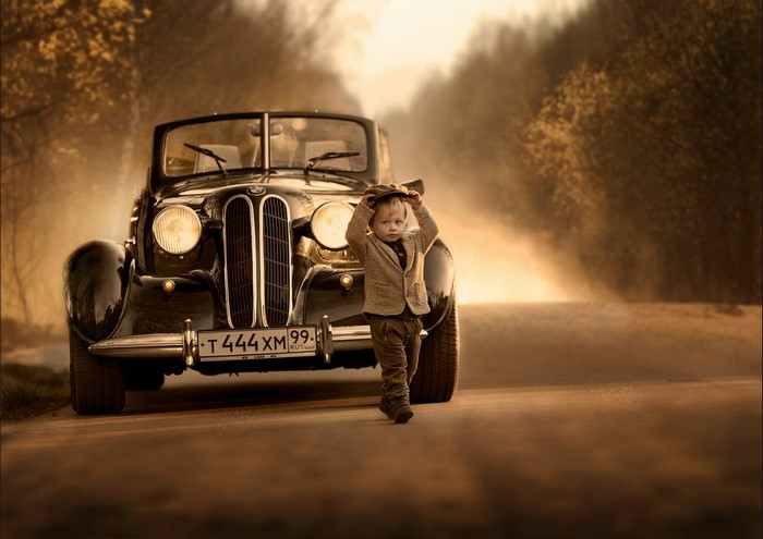 Boy with vintage car on a road
