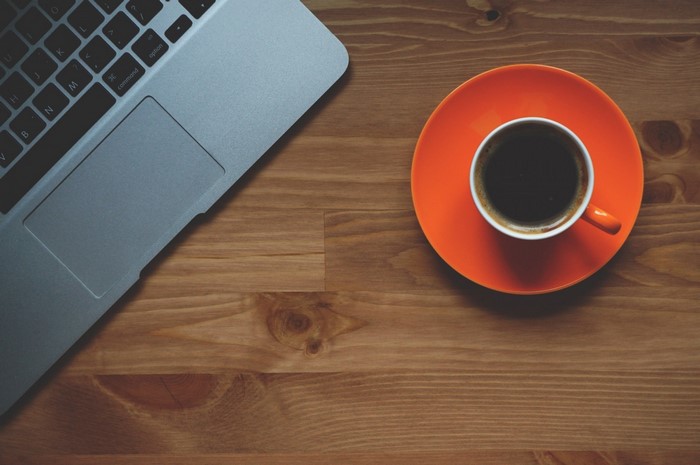 Laptop and coffee cup on a wooden desk