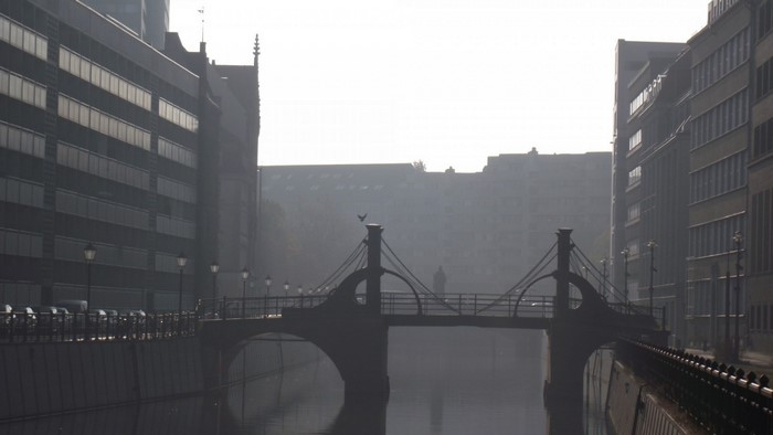 Misty bridge over a river in a city with buildings