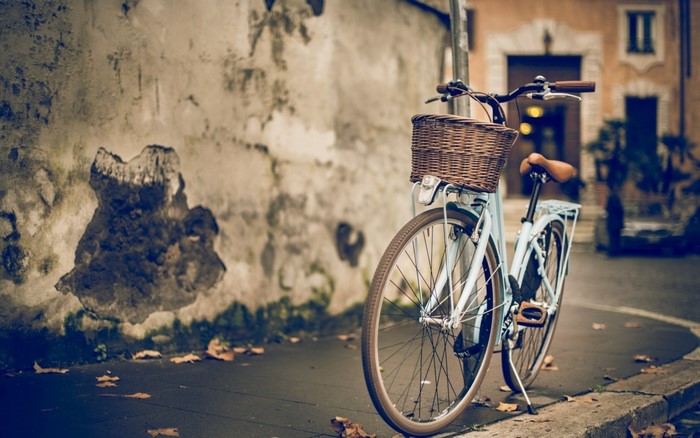 Blue bicycle with a wicker basket parked by a textured wall