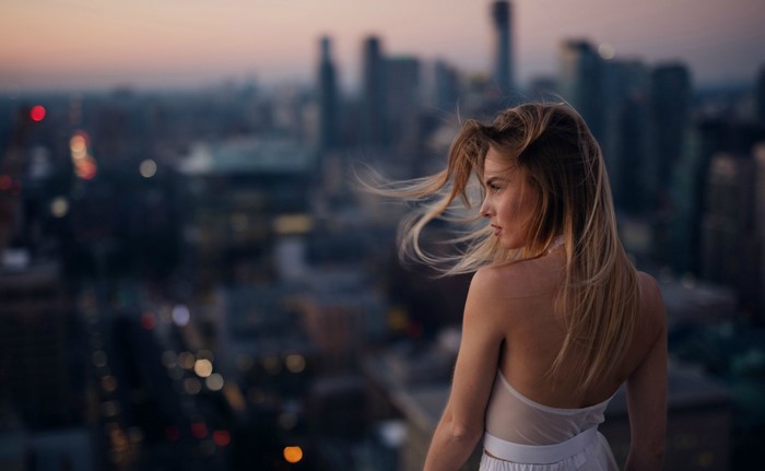 Woman on a rooftop overlooking a city at dusk