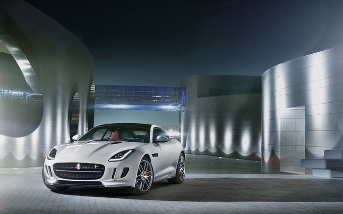 White Jaguar F-Type sports car parked at modern architecture at night