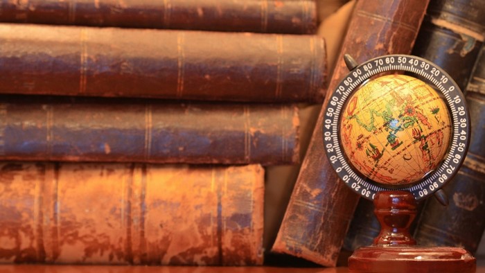 Stack of old books with a miniature globe