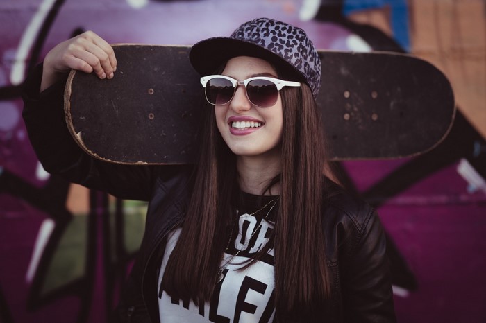 Young woman with skateboard and sunglasses