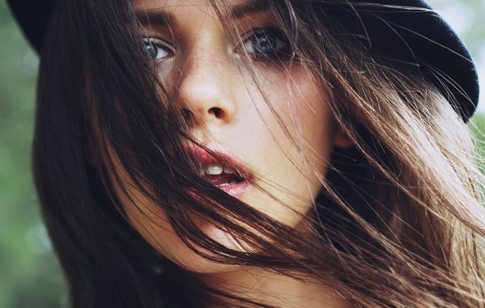 Close-up portrait of a young woman with hair blowing across her face