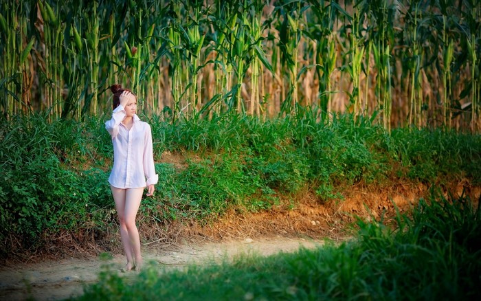 Woman Standing in Sunlit Green Field
