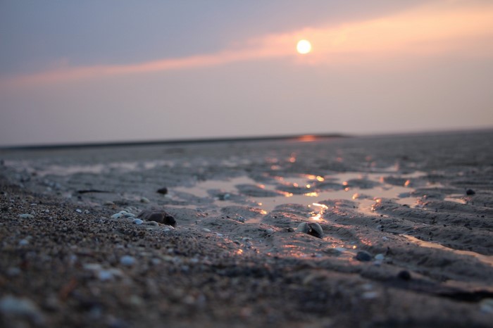 Sunset over a sandy beach with shallow water