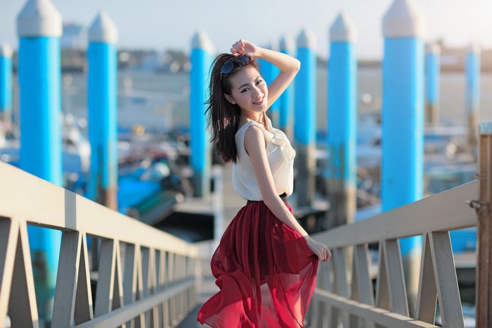 Asian woman in a white top and red skirt on a pier