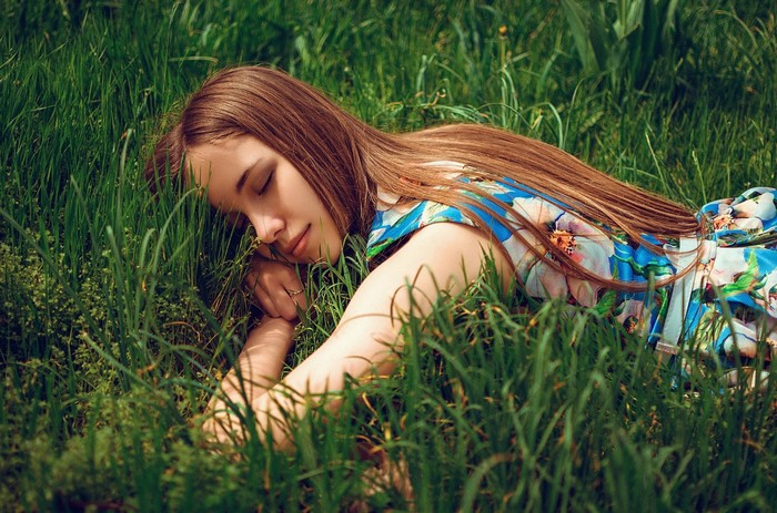 Woman sleeping in a colorful floral dress on grass