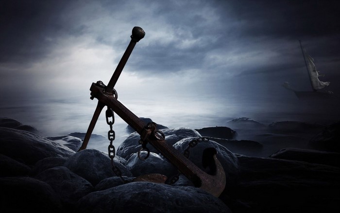 Anchor on rocky shore with ship in foggy sea