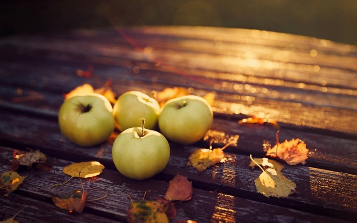 Apples and autumn leaves on a wooden table