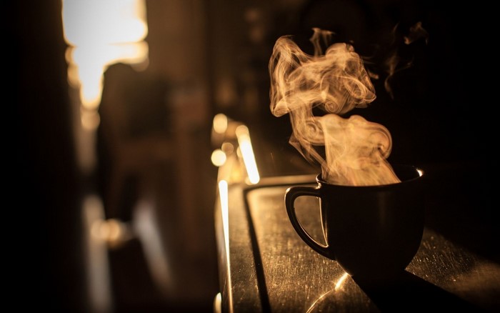Steaming cup of coffee in the dark