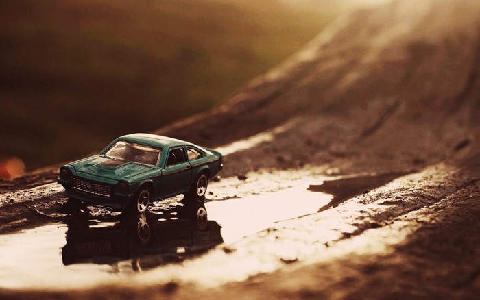 Teal Hot Wheels Chevrolet Vega toy car on wet surface