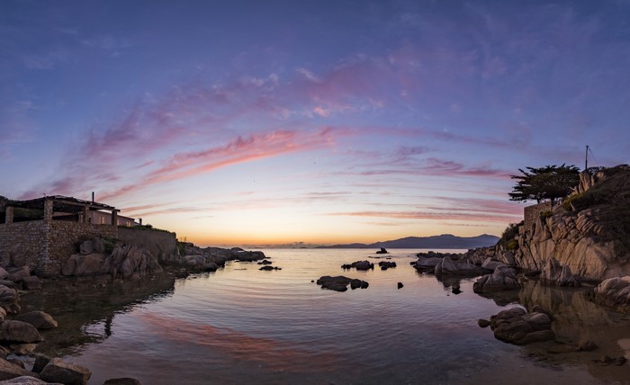 Coastal landscape at sunset with rocky shore and calm sea
