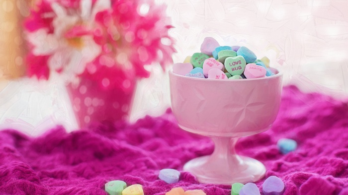 Heart-shaped candies in a pink bowl with flowers