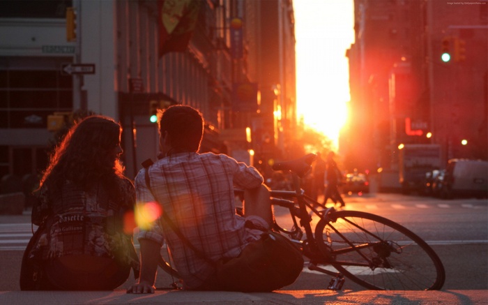 Couple sitting on street at sunset with bicycle