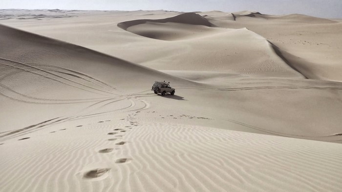 Off-road vehicle driving through vast sand dunes