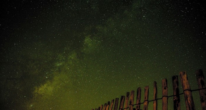 Night sky with stars and Milky Way over a wooden fence