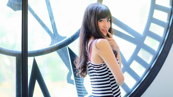 Asian woman posing in front of a clock face