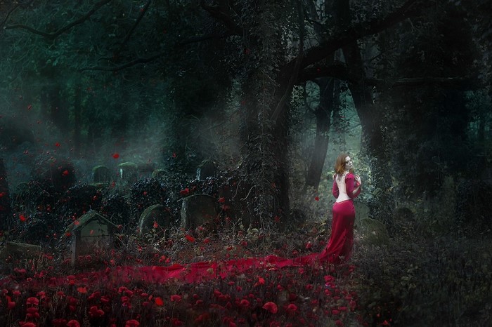 Woman in red dress in a dark forest cemetery
