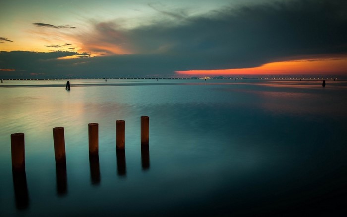 Sunset over the sea with wooden posts
