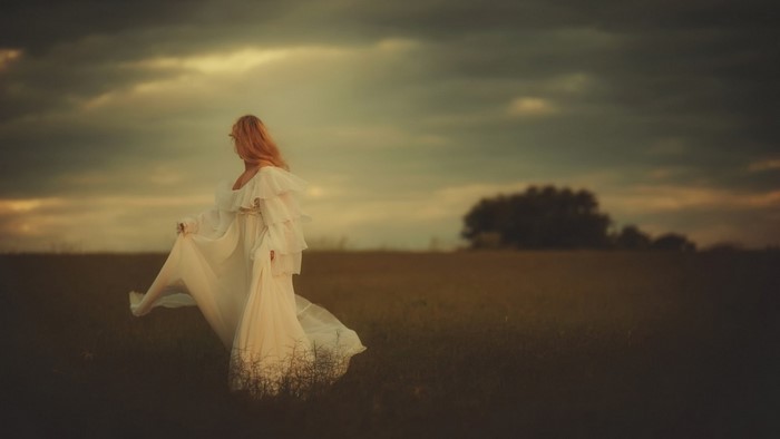 Woman in white dress in a field at sunset