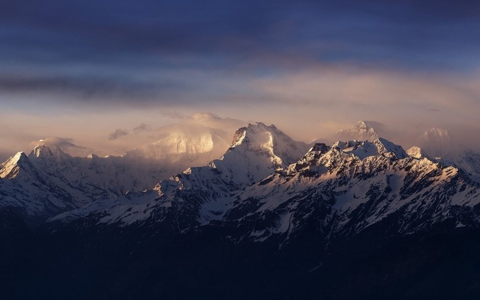 Snow-capped mountains at sunset with clouds