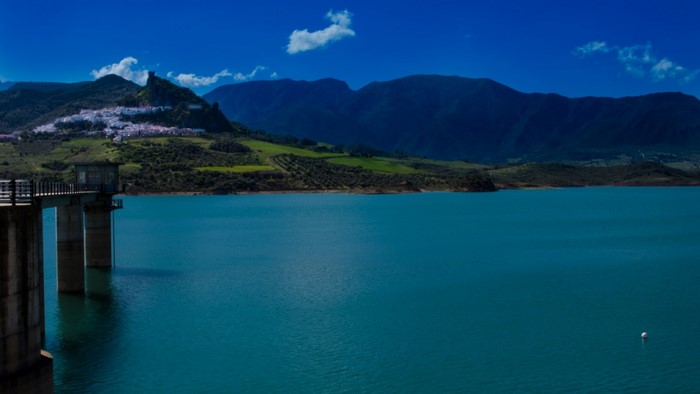 Reservoir with a village on a hill and mountains