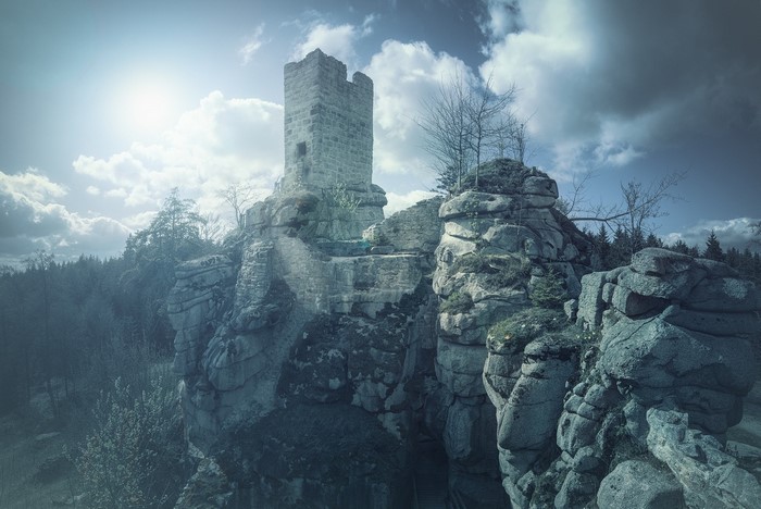 Ruined castle on a rocky summit with dramatic clouds