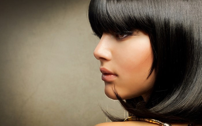 Woman with black bob haircut and bangs in profile